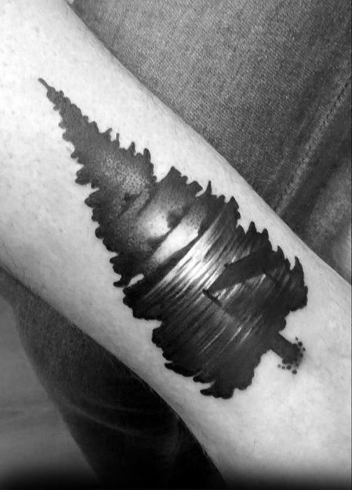 Creative blackwork tattoo shaped like a pine tree, with a hidden lake and canoe scene formed by negative space across the center.