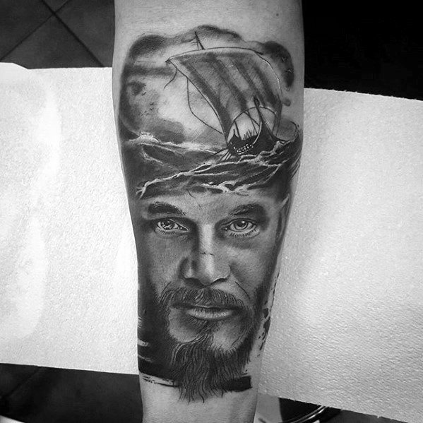 Forearm tattoo of a man's face with a detailed ship and large waves above it