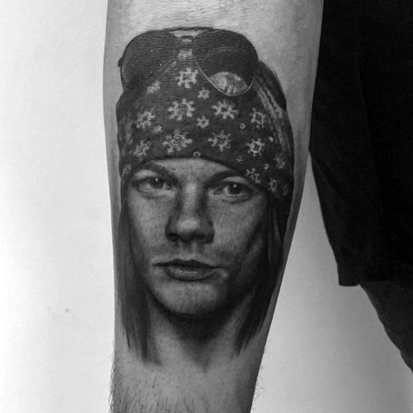 Realistic black and grey tattoo of a long-haired man wearing a patterned bandana and sunglasses, inspired by Guns N' Roses style.