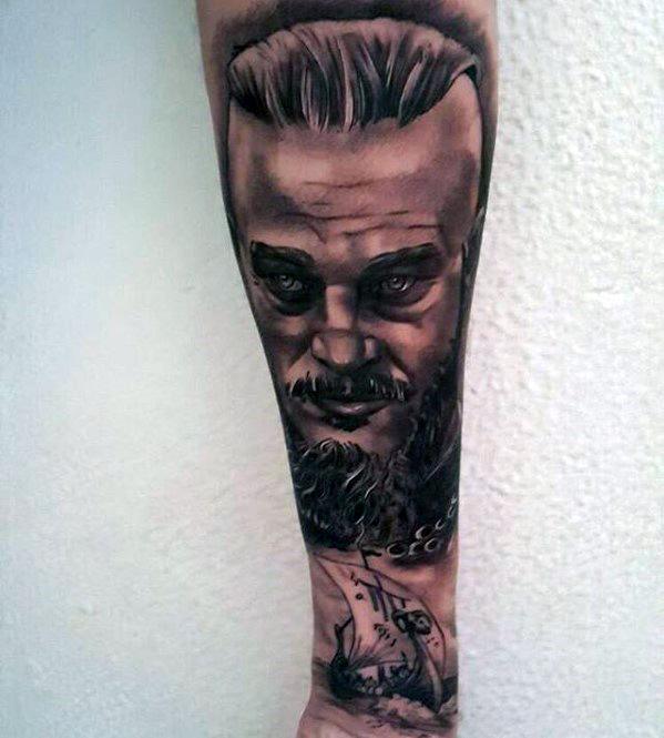 Forearm tattoo featuring a detailed portrait of a man with a beard and slicked-back hair above a ship