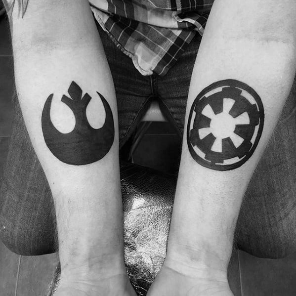 Forearms with Rebel Alliance and Galactic Empire symbols tattooed in black ink