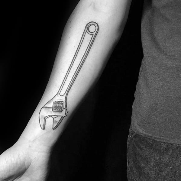 Minimalist black line tattoo of an adjustable wrench along the forearm, designed with clean, simple outlines.