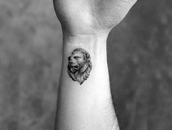 Wrist tattoo for men featuring a small, realistic lion head design in fine black and grey detail.