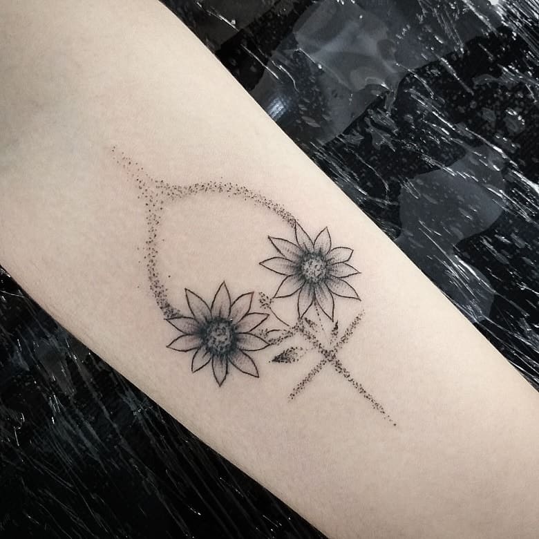 Elegant fine-line tattoo featuring two detailed sunflowers with a Venus symbol, designed with soft dotwork shading