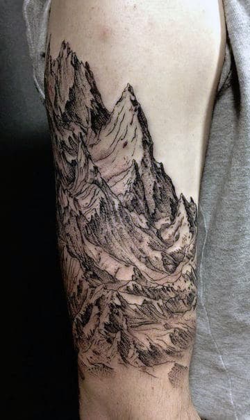Tattoo of a detailed mountain range covering a person's upper arm