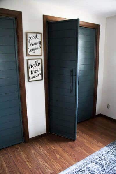 A stylish interior with a dark green sliding closet door featuring a modern slatted design, complemented by decorative wall signs