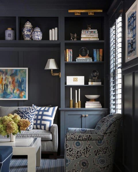 Cozy living room with dark shelves, patterned chair, decorative jars, and an abstract painting