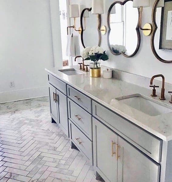 Elegant double vanity with marble countertop, gold fixtures, and decorative mirrors.