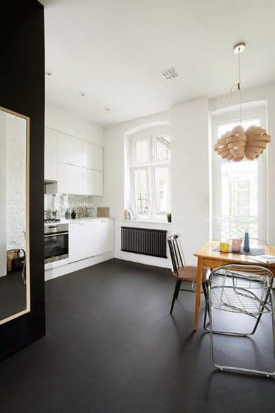 Minimalist kitchen with white cabinets, a wooden dining table, modern lighting, and concrete floor in natural light
