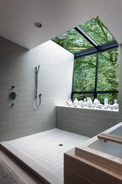 Modern bathroom with skylight, grey tiles, white fixtures, and view of trees outside