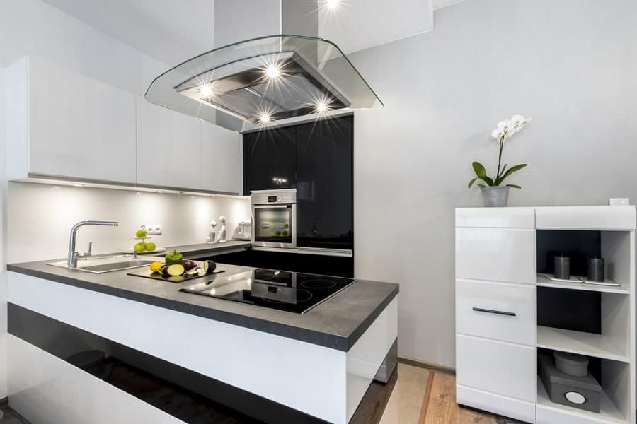 Modern kitchen with sleek cabinets, a large island featuring an induction cooktop, built-in oven, and orchid on a shelf