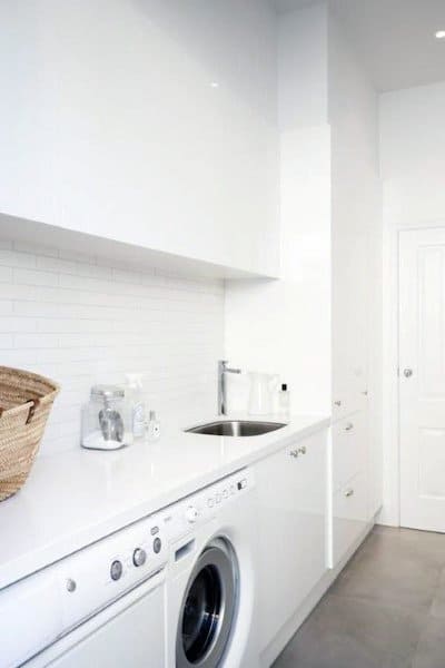 Minimalist laundry room with white cabinets, white appliances, and a sleek countertop.