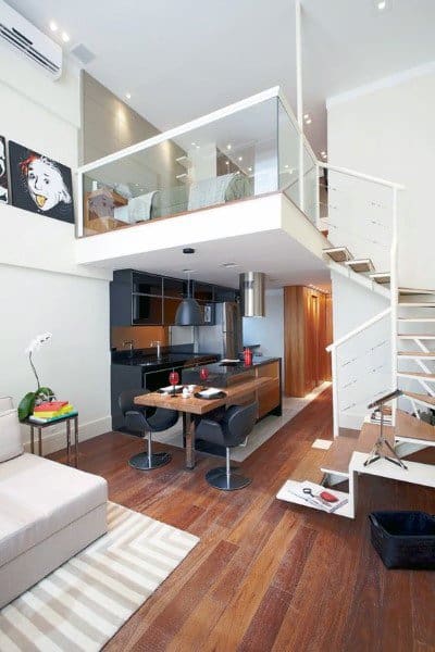 Compact loft with glass-walled bedroom, modern kitchen, and cozy wooden dining area.
