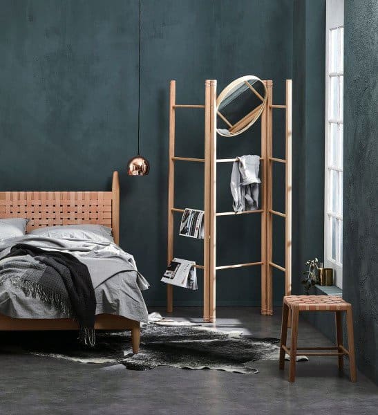 Scandinavian-style bedroom with navy walls, wooden furniture, and modern pendant lighting.