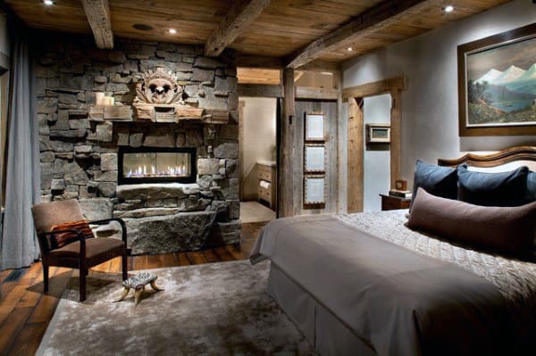 Rustic luxury bedroom with stone fireplace, wooden beams, and cozy decor accents.