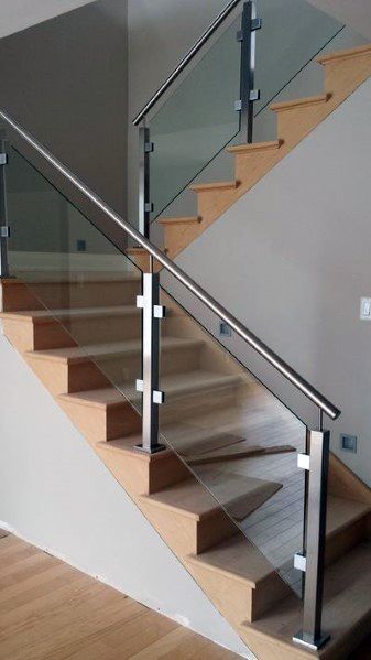 Wooden staircase with sleek glass railing and metal accents in a modern home.