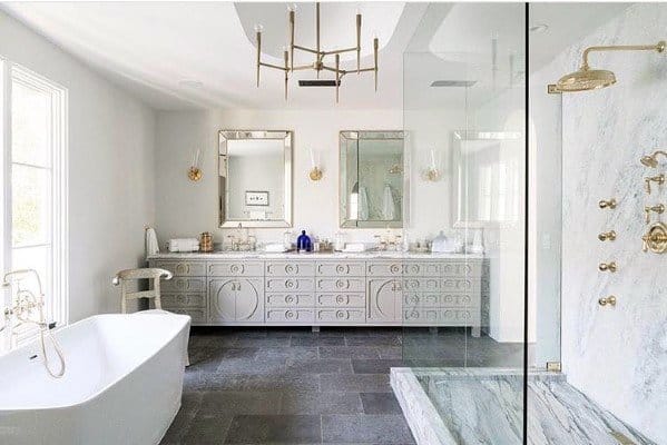 Spacious bathroom with freestanding tub, marble shower, gold fixtures, and modern chandelier.