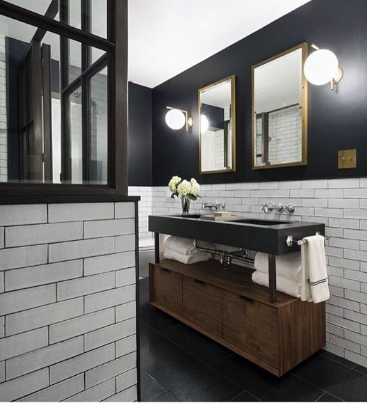 Modern bathroom with black walls, white subway tiles, and a sleek wooden vanity.