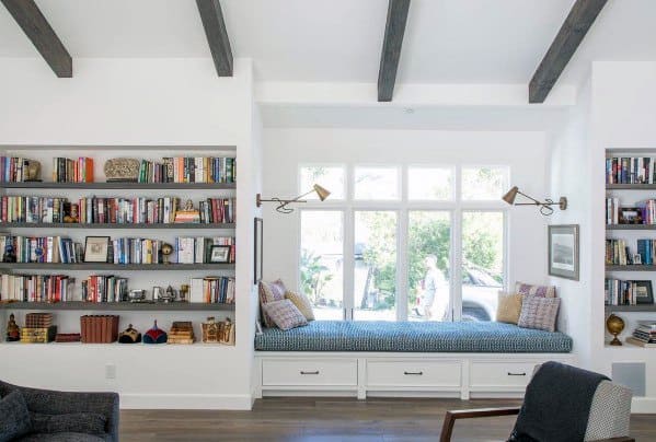 Bright living room with built-in bookcases, cozy window seat with storage, and exposed ceiling beams