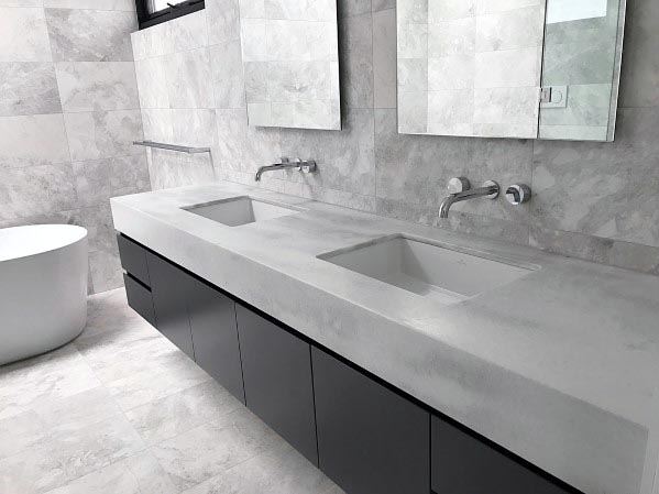 Minimalist grey bathroom with sleek double sinks, wall-mounted faucets, and a freestanding tub.