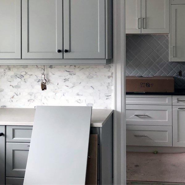 Light grey kitchen cabinets with marble backsplash and a clean, modern design.