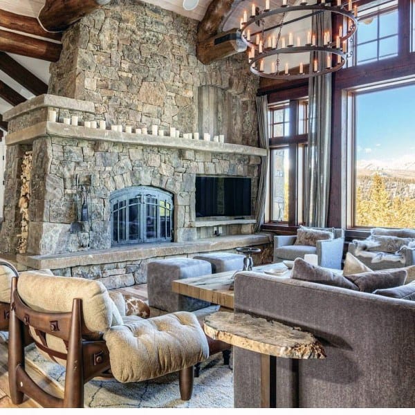 Luxurious log cabin living room with stone fireplace, modern seating, and large windows.
