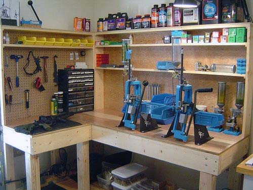 Fully equipped reloading bench with dual blue presses, pegboard tool organization, and shelves stocked with supplies