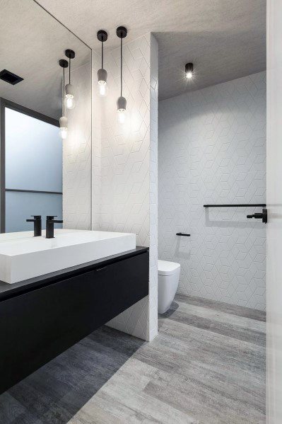 White modern bathroom with pendant lights, a black vanity, and geometric tiles