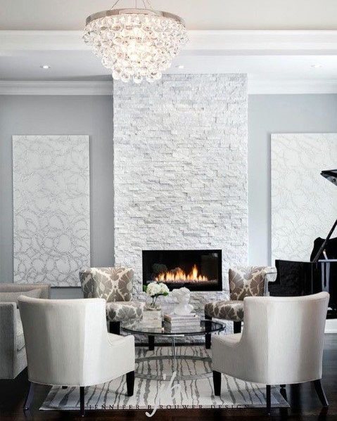 Elegant white stacked stone fireplace in a sophisticated living room with chic decor and a crystal chandelier