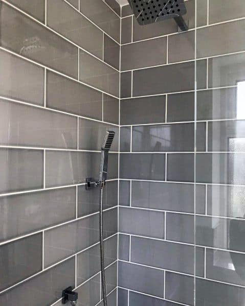 Shower with grey subway tiles and a square showerhead