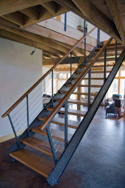 Modern floating stairs with wooden steps, metal railing, and cable design in an open-plan interior.