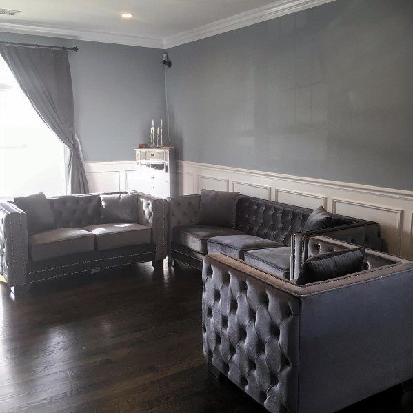Gray tufted sofas in a modern living room with chair rail detailing, dark flooring, and light gray walls
