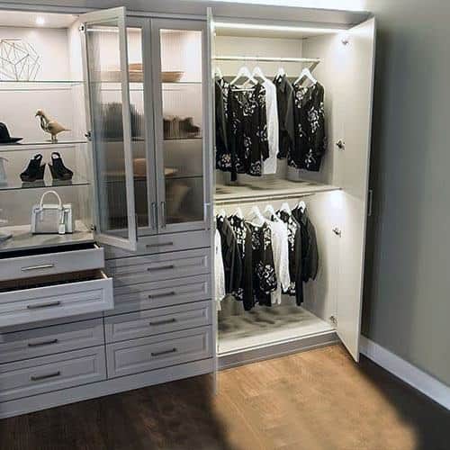 Large white wardrobe with open closet doors, showcasing organized hanging clothes.