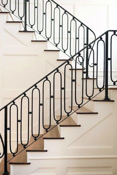 U-shaped staircase with black wrought iron railing and white paneled walls in a traditional interior design.