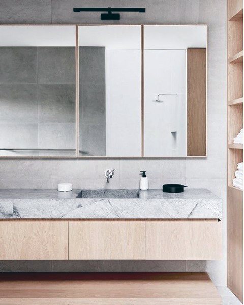 Modern floating wood vanity with marble countertop and large mirrored cabinet.