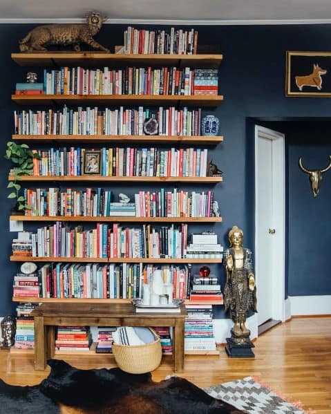 Colorful books, statues, and decor enliven a bookshelf against a dark wall