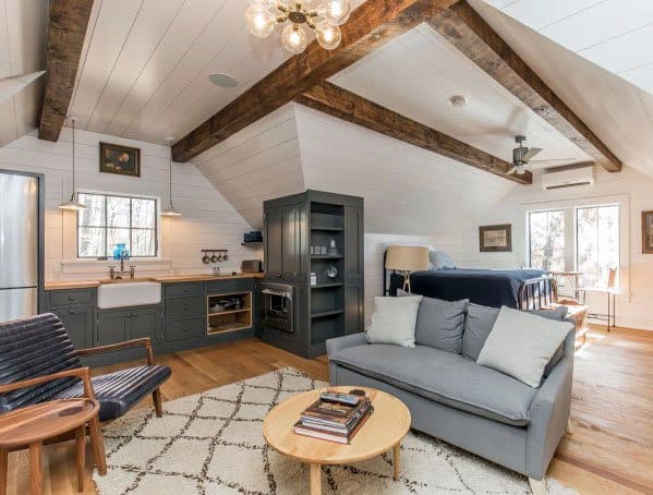 Rustic studio with exposed beams, farmhouse kitchen, cozy seating, and natural light.