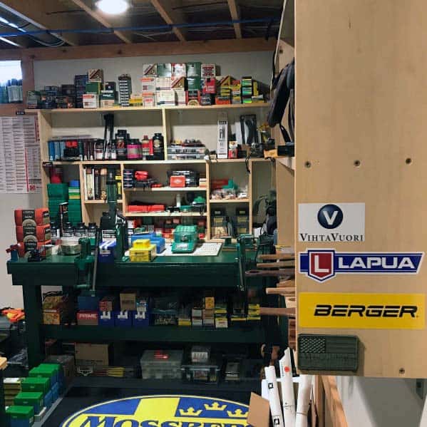 Fully stocked reloading bench with green presses, organized shelves filled with components, and a tidy workspace layout