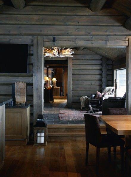 Rustic log cabin interior with wooden walls, cozy seating, and warm natural lighting.