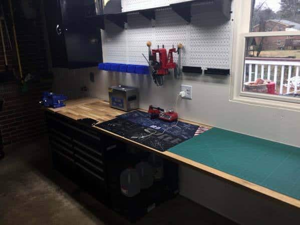 Clean and modern reloading bench with a mounted red press, pegboard storage, and a spacious wooden work surface