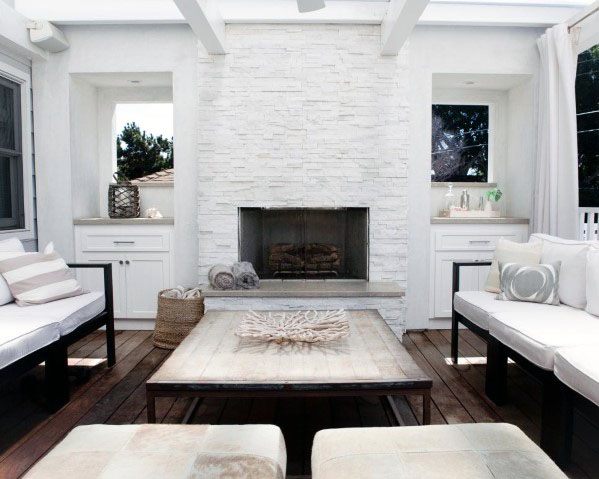 Bright white stacked stone fireplace in a cozy outdoor seating area with neutral decor and wooden flooring