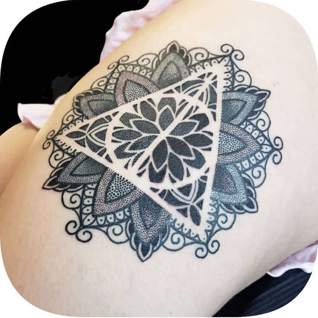 Intricate Deathly Hallows tattoo with a mandala design, featuring detailed dotwork and floral patterns, creating a striking geometric effect.