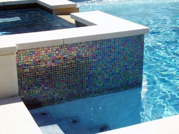 Iridescent mosaic tiles on a pool wall with vibrant colors and a sleek modern design.