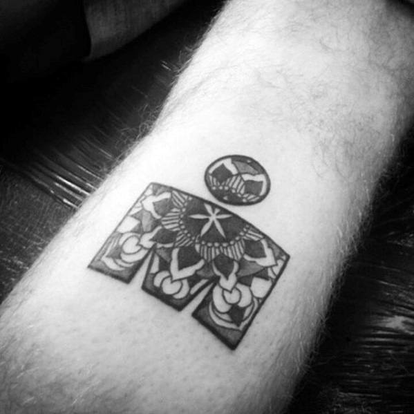 Blackwork Ironman logo tattoo on a forearm, filled with symmetrical tribal and floral patterns in bold, intricate detailing.