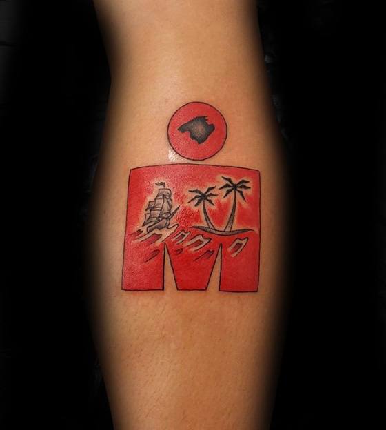 Red Ironman logo tattoo featuring a ship, ocean waves, and palm trees, with the Hawaiian island outline in the circular dot above.