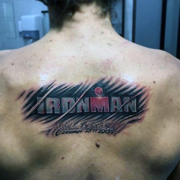 Ironman logo tattoo with a scratched effect, featuring the word "IRONMAN" in bold letters and a red logo, along with the event name and date at the bottom.