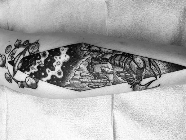Black and white tattoo of a lobster and planets on an arm, in geometric shape, on white cloth