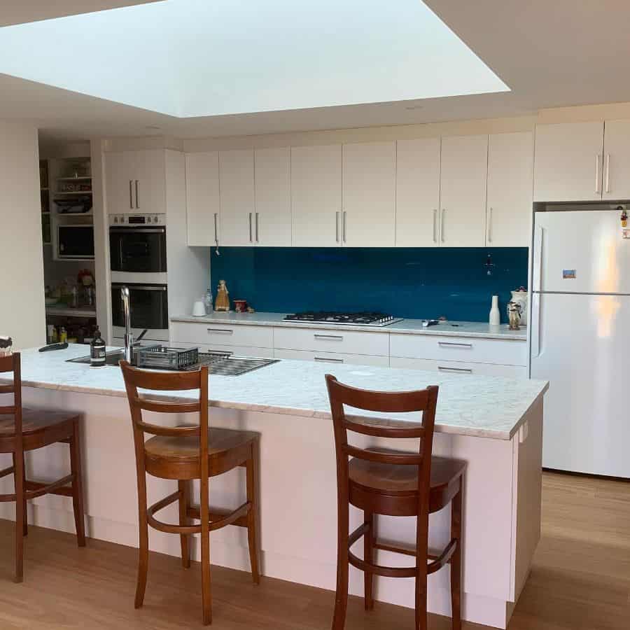 large modern kitchen white cabinets marble top island wood chairs