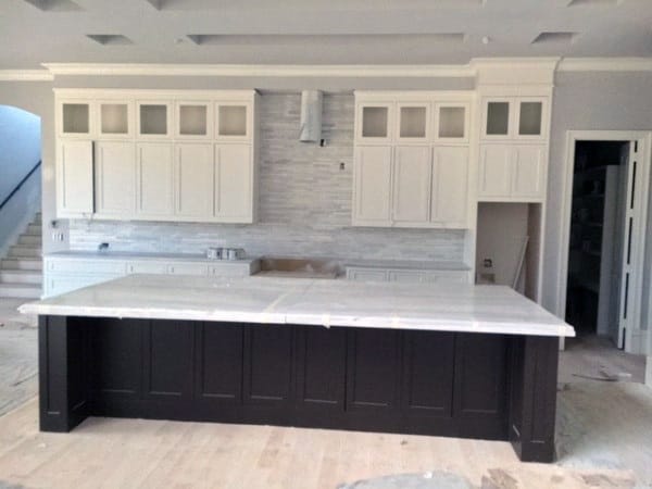 Modern kitchen featuring a spacious island, white cabinets, and light wood flooring