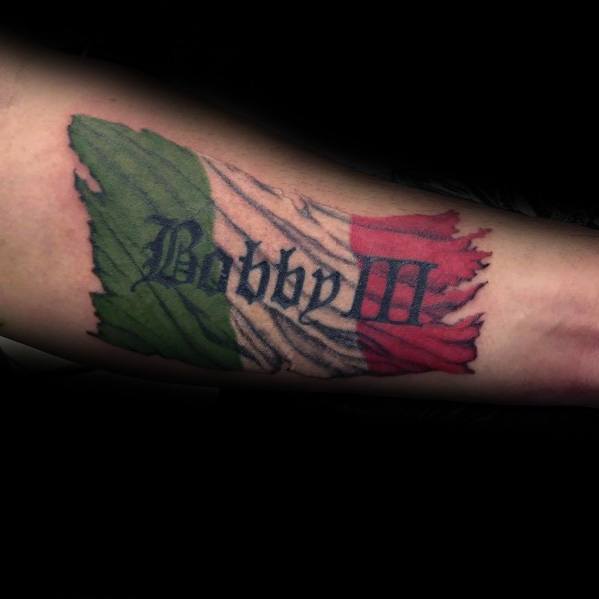 Forearm tattoo of a tattered Italian flag with the name "Bobby M" in bold script, symbolizing heritage, pride, and personal identity.